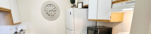 A small kitchen with white cabinets and a black microwave.
