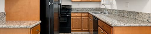 A kitchen with wooden cabinets and a black refrigerator.
