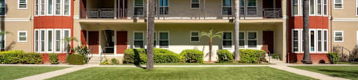A row of apartment buildings with a green lawn in front.