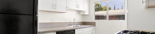 a kitchen with white cabinets and a black refrigerator
