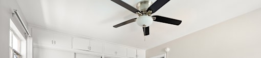 an empty room with white cabinets and a ceiling fan