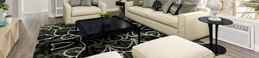 A modern living room with a black and white patterned rug, a white sofa, a black coffee table, and a large window with a view of the city.