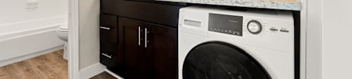 a white washer and dryer in a bathroom with a sink and a mirror