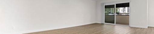 an empty living room with wood flooring and a sliding glass door