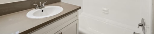 A white bathroom with a sink and a shower.