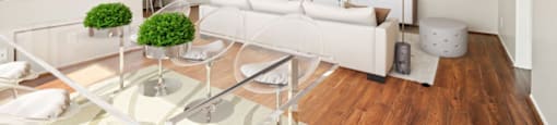 A modern living room with a glass coffee table and white furniture.