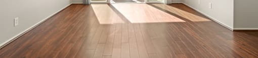 A room with a wooden floor and a glass door leading to a balcony.