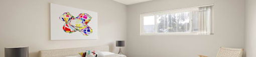A bedroom with a large bed, a chair, and a painting on the wall.