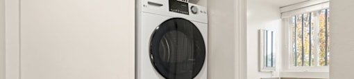 A white front loading washing machine in a laundry room.