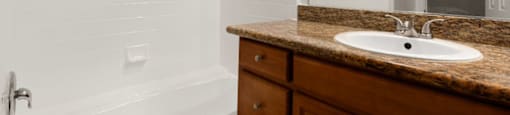 A bathroom with a brown counter top and a white sink.