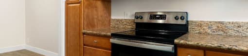 A kitchen with wooden cabinets and a black stove top oven.