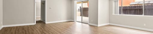 an empty living room with a large window and hardwood floors