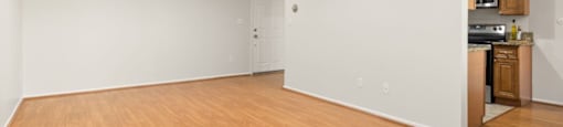 an empty living room with wood flooring and a kitchen at Lombardi Apartments, California, 91367