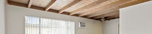 Canoga Park CA Luxury Apartments for Rent - Parthenia Terrace - Empty Living Room with Large Window, AC, Ceiling Fan, and Wood-Style Flooring.