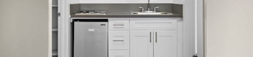 a small kitchen with white cabinets and a stainless steel dishwasher