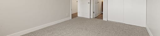 a bedroom with white walls and carpet and a door to a closet