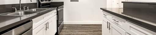 A kitchen with white cabinets and a wood floor at The Reserve at Warner Center Apartments, Woodland Hills, California