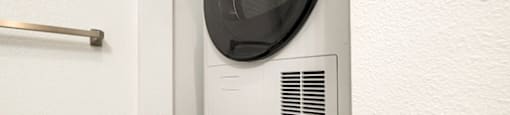 A white washing machine is installed in a wall at The Reserve at Warner Center Apartments, CA, 91367