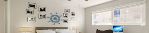 A bedroom with a bed, a chair, a ceiling fan, and pictures on the wall.