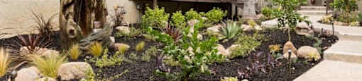 the front yard of an apartment building with landscaping and rocks