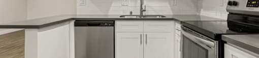 a kitchen with white cabinets and black counter tops