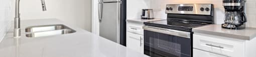 Apartments in Encino, CA- Brookside Terrace Apartments- Kitchen Area with Stainless-Steel Appliances, White Modern Cabinets, and Quartz Countertops