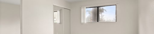 A room with a large mirror on the wall and a carpeted floor.