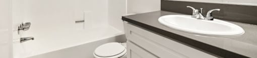 A white bathroom with a toilet, sink, and shower.