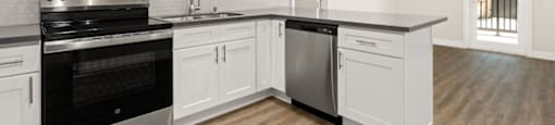 a kitchen with white cabinets and a stove and a microwave at Woodland Trio Apartments, North Hollywood, CA