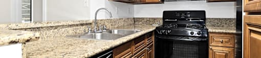 a kitchen with wooden cabinets and a black stove top oven at Woodland Trio Apartments, North Hollywood