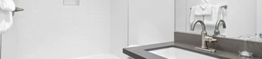 1 Bedroom Apartments in Encino, CA - Brookside Terrace - White Bathroom, with a Shower and Tub, Silver Hardware, Tile Walls, Wood-Style Flooring, Grey Countertops on the Vanity, White Cabinets, and a Large Mounted Mirror