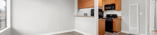 an empty living room with a kitchen in the background