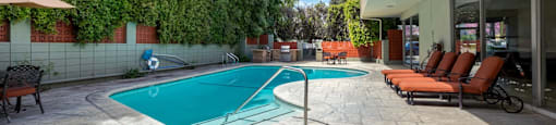 Encino CA Apartments for Rent - White Oak Terrace - Blue Outdoor Pool with Poolside Seating with Greenery on Enclosure
