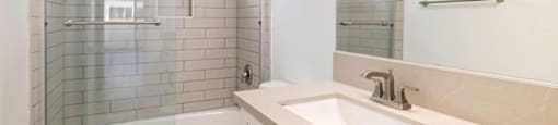 A white bathroom with a glass shower door and a white toilet.