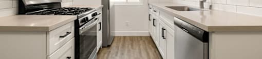 A kitchen with white cabinets and a stainless steel dishwasher.