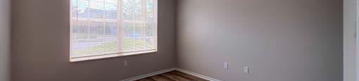 A room with wooden flooring and a window letting in light.