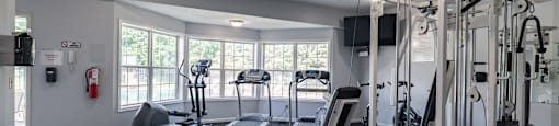 A well-equipped gym with a variety of machines and a fire extinguisher on the wall.