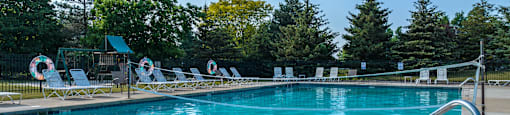 A large swimming pool surrounded by trees and lounge chairs.