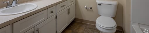 A white toilet sits next to a sink in a bathroom. at Highlands of Heritage Woods Apartments, Ohio