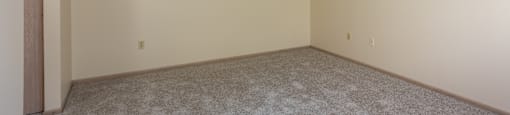 A room with a carpeted floor and a door on the left side. at Highlands of Heritage Woods Apartments, Copley, OH, 44321
