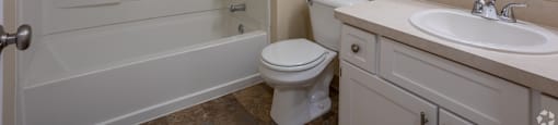 A white bathroom with a toilet, sink, and bathtub. at Highlands of Heritage Woods Apartments, Copley 44321