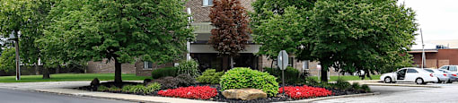 A tall building with a grey facade and a green tree in front of it.
