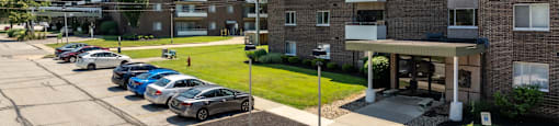 A parking lot with cars and two apartment buildings.