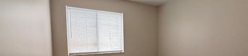 A room with a window and carpeted floor.