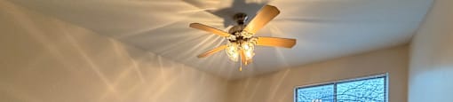 A room with a ceiling fan and carpeted floor.