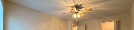 A room with a ceiling fan and carpeted floor.