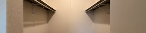A small, empty room with a carpeted floor and two metal shelves.