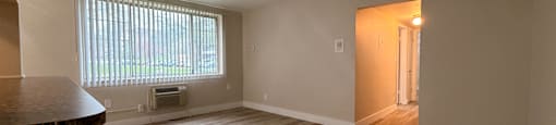 A room with wooden flooring and a window with blinds.