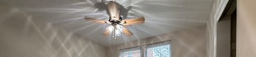 A room with a ceiling fan and a window.