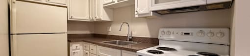 A kitchen with white appliances and wooden floors.
